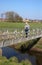 Lady on metal footbridge, small river, Pilling