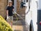 A lady motorhome owner cleans her recreational vehicle with a hose pipe.Spray can be seen coming from the pipe as lady cleans van