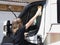 A lady motorhome owner cleans her recreational vehicle side window wearing gloves with a sponge and foam