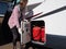 A lady motorhome owner opens a gas locker door wearing gloves.LPG gas bottles can be seen.