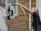 Lady motorhome owner stands cleaning her recreational vehicle with a hose pipe.Spray can be seen from the pipe