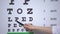 Lady ophthalmologist checking eyesight, showing letters on chart, focused vision