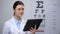 Lady optometrist checking results in tablet and smiling to camera, technologies