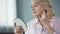 Lady over 50 looking at herself in mirror, rejoicing at result of skin lifting