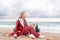 Lady in plaid shirt holding a gift in his hands enjoys beach with Christmas tree. Coastal area. Christmas, New Year