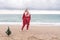 Lady in plaid shirt holding a gift in his hands enjoys beach with Christmas tree. Coastal area. Christmas, New Year