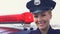 Lady police officer in cap standing near patrol car and smiling, law protection