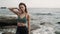 Lady poses for camera touching long hair against ocean waves