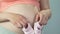 Lady pregnant with child holding baby shoes against belly, expecting daughter