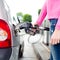 Lady pumping gasoline fuel in car at gas station.