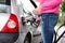 Lady pumping gasoline fuel in car at gas station.