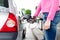 Lady pumping gasoline fuel in car at gas station.