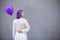 Lady with purple hair with balloon standing turn her back looking to side