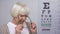 Lady retiree putting on spectacles, smiling and reading on smartphone, blindness