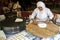 A lady rolls Turkish flat bread before placing it onto a hot plate cooker.