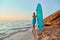 Lady on sandy coastline on sunset. Calm sea, empty beach and surfboard. Idea of summer time and surfing, copy space