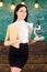 Lady scientist holds book and microscope, chalkboard on background, copy space. Lady in formal wear on calm face in