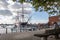 Lady seated on a bench in front of HMS Warrior, Britain`s first iron-hulled, armoured battleship, moored at Portsmouth Dockyard, H