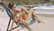 Lady with Smartphone Sits in Beach Chair on Coast