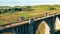 A lady with sports inventory is walking along a stone bridge