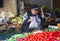 Lady stall holder with her hand raised as she fills a plastic bag with fresh vegetables at the Mahane Yehuda market in J