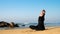 Lady stretches back practicing yoga exercises against ocean