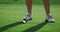 Lady swinging golf club on grass course. Woman legs posing on golfing fairway.