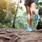 Lady trail runner walking in park with close up of trail running shoes