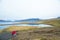 A lady traveller sitting on rocks along the road is looking at t