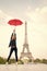 Lady with umbrella posing in front of Eiffel Tower, sky background. Lady tourist sporty and active walks in Paris city