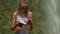 Lady in violet top reads diary book on large rock