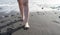 Lady walking on the sand with refreshment wet legs in black sand beach on an island. Sandy Fingers in the foot