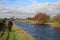 Lady walking on towpath on canal bank in autumn