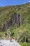 Lady walking on valley footpath, waterfall at side