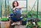 Lady watering spring early potatoes grown in the greenhouse, in containers, 2.