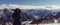 A lady wearing a hooded jacket looks down from the mountain into the wide open valley