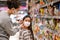A lady  wearing a protective mask puts a face mask on a daughter in  supermarket. Safety during COVID-19 outbreak. Epidemic of
