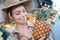 Lady wearing straw hat and holding pineapple