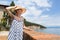 Lady wearing striped summer dress and straw hat relaxing on vaction enjoying view over beach at Moscenicka Draga, Istria