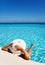 Lady with white hat relaxes in swimming pool