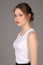 Lady in white singlet standing profile. Close up. Gray background