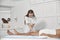 Lady in white uniform massages legs of middle aged man in contemporary clinic