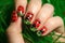 ladybird nail art on a hand amidst green grass