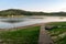 Lagoa VÃ¡rzea das Flores, with a wooden bridge and woods in the background.