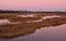 Lagoon of Caorle at sunset: spectacular sunset with a pink sky reflected in the water among the reeds