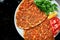 Lahmacun is a popular Turkish dish. Thin crispy tortilla with minced lamb, tomatoes and bell pepper on black background