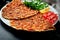 Lahmacun is a popular Turkish dish. Thin crispy tortilla with minced lamb, tomatoes and bell pepper on black background