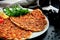 Lahmacun is a popular Turkish dish. Thin crispy tortilla with minced lamb, tomatoes and bell pepper on black background