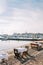 Laid tables with chairs stand on the beach near the pier with yachts