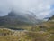 Lake Alnesvatnet with snow capped mountain peak and rainbow. View from scenic road 63 in the Reinheim national Park near the